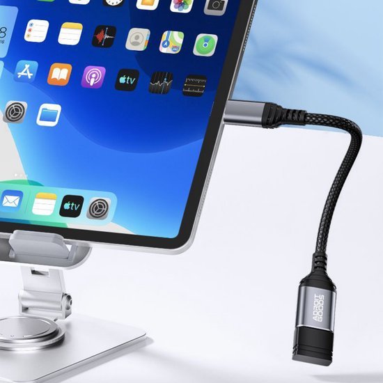 Zwarte gevlochten adapterkabel aangesloten op tablet met metalen standaard in moderne omgeving