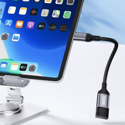 Zwarte gevlochten adapterkabel aangesloten op tablet met metalen standaard in moderne omgeving