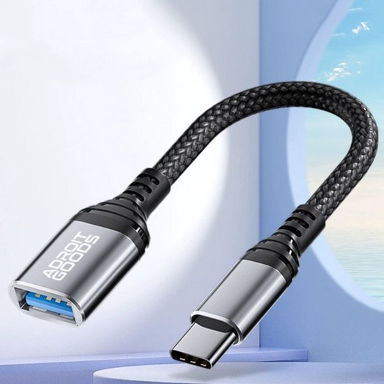 Zwarte gevlochten USB-C naar USB 3.0 adapterkabel met metalen behuizing naast raam met zeezicht