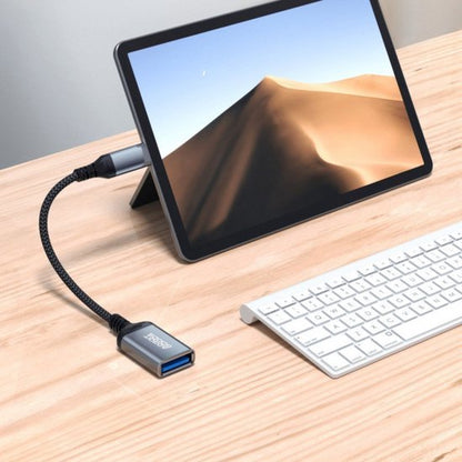 Tablet met zandduin achtergrond verbonden via kabeladapter aan toetsenbord op houten tafel