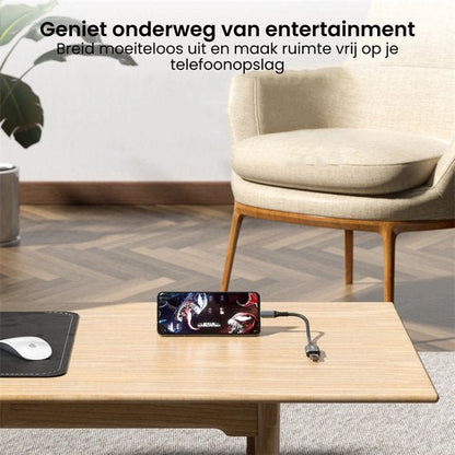 Smartphone die video afspeelt op een houten tafel naast een bureaublad met muis en beige stoel erbij