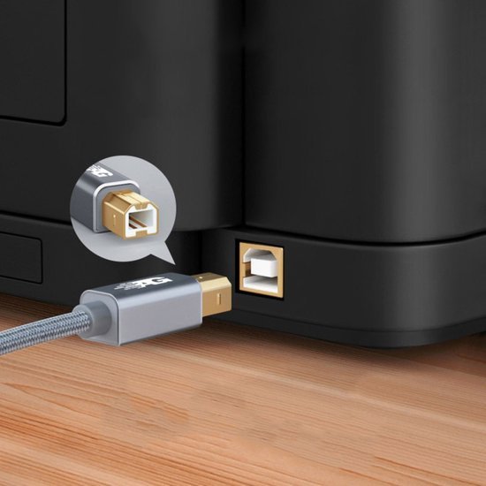 Grijs USB-kabel met metalen connector wordt aangesloten op een zwarte printerpoort op houten oppervlak.