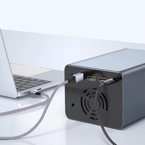 Zwarte externe behuizing met ventilator en twee blauwe USB-poorten, verbonden met laptop.