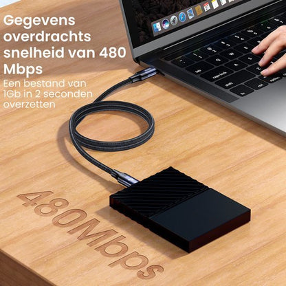 Externe harde schijf verbonden met laptop via kabel op houten tafel met overdrachtssnelheid tekst