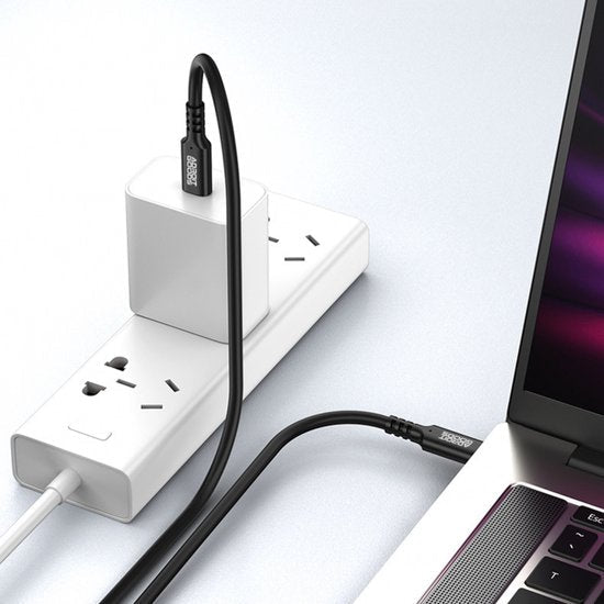 Zwarte USB-C-kabel verbonden met een laptop en een wit stroomadapter in een stekkerdoos