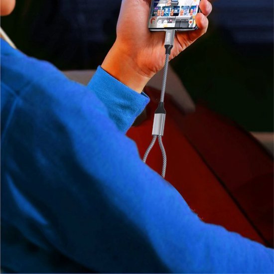 Persoon houdt smartphone vast die verbonden is met een stevig gevlochten oplaadkabel