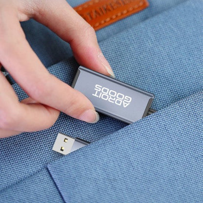 Hand die USB-stick met logo AdroitGoods in een blauwe stoffen tas stopt.