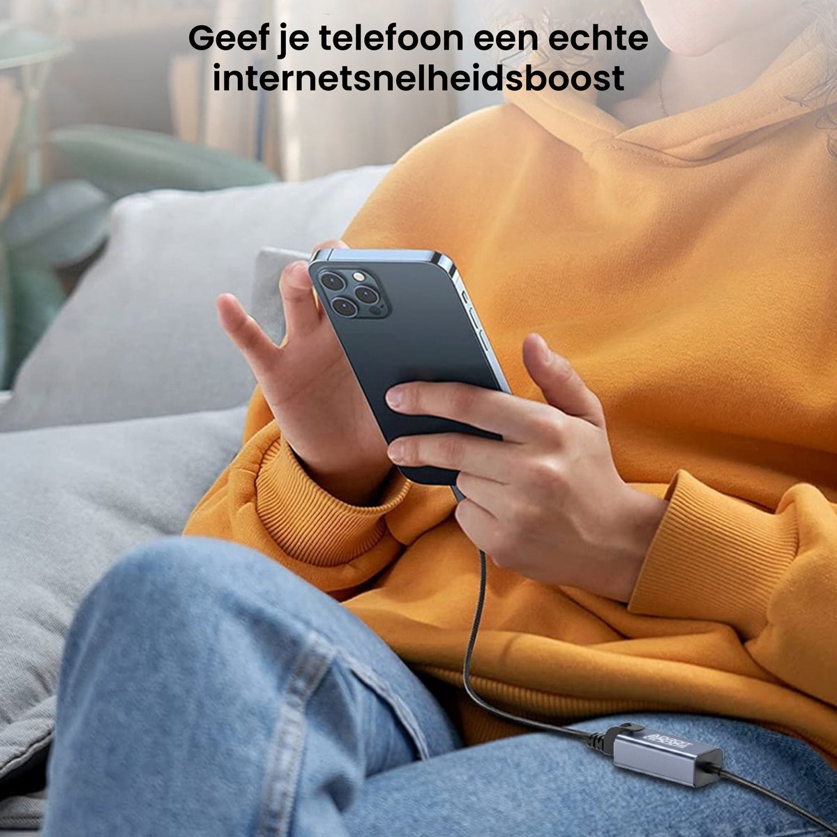 Persoon in oranje trui gebruikt smartphone met aangesloten kabel en adapter op bank