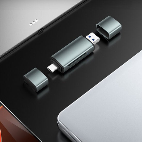 Grijze USB-stick met afneembare doppen tussen een tablet en een laptop geplaatst