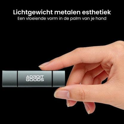 Hand houdt lichtgewicht metalen object met de tekst Adroit Goods op zwarte achtergrond