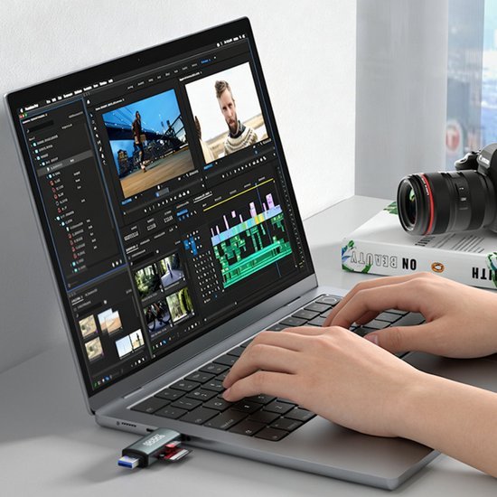 Persoon die videobewerking doet op laptop met camera en geheugenkaartlezer op bureau