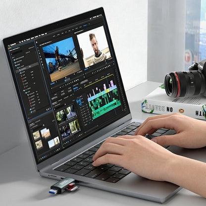 Persoon die videobewerking doet op laptop met camera en geheugenkaartlezer op bureau