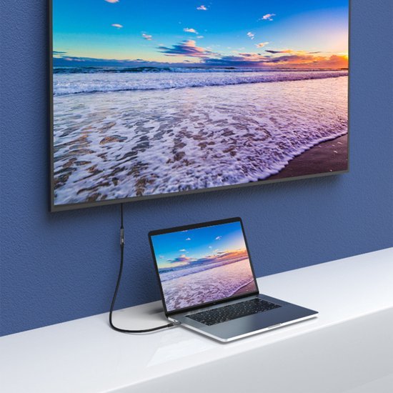 Laptopp met HDMI-kabel verbonden aan groot scherm met uitzicht op zee bij zonsondergang