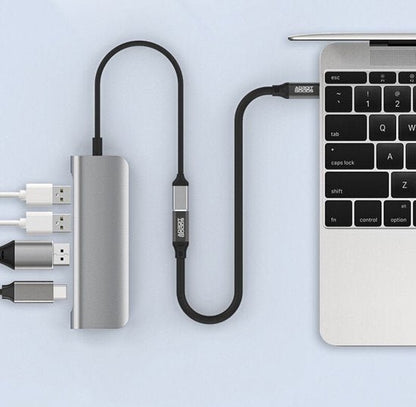 Adapterkabel met meerdere aansluitingen verbonden met laptop en accessoires in grijze stijl