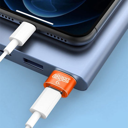 Smartphone aangesloten op powerbank met oranje AdroitGoods adapter en witte kabels