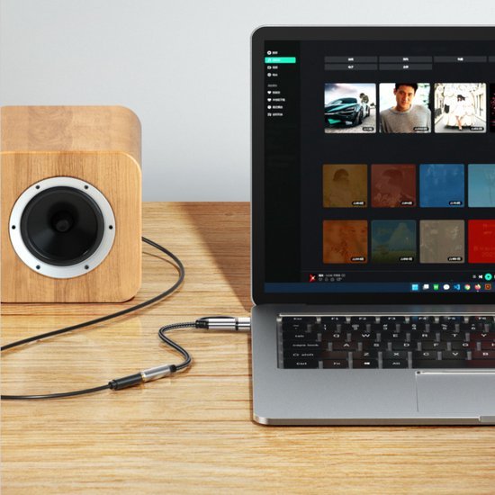 Houten speaker naast laptop op houten tafel, met audiosoftware zichtbaar op scherm