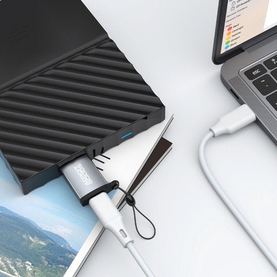 externe harde schijf met aangesloten USB-kabel naast laptop op een witte ondergrond