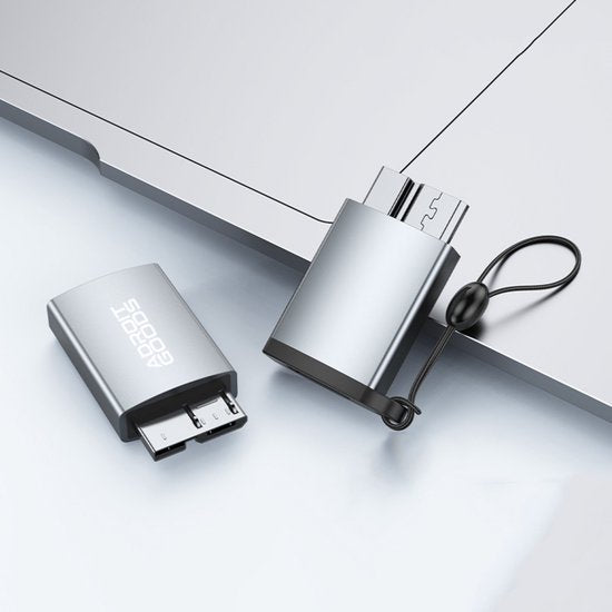 Elegant zilverkleurige usb-adapter met micro-usb aansluiting naast een laptop