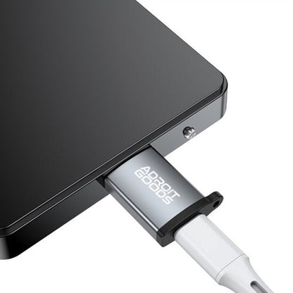 Zilveren AdroitGoods adapter aangesloten op een zwart elektronisch apparaat met witte kabel.