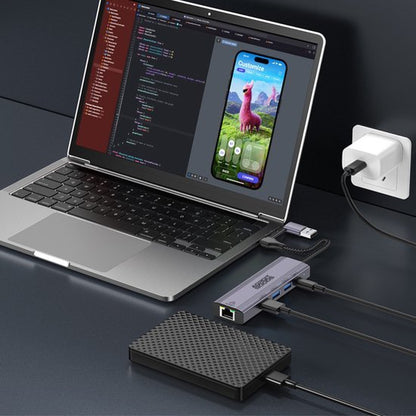 Laptop met programmeercode en smartphone app, aangesloten op multifunctionele USB-hub en externe opslag