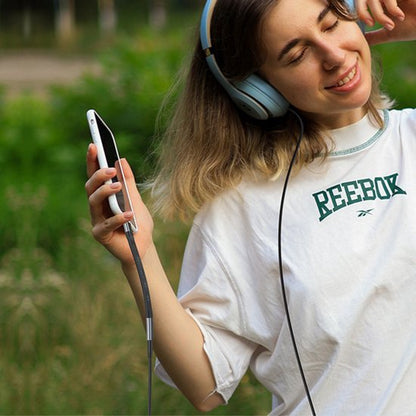 Vrolijke jonge vrouw geniet van muziek met grote koptelefoon en smartphone in hand buiten