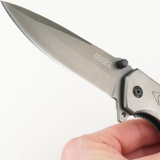 Close-up van een hand die een scherp vouwmes met metalen lemmet en merkgravure vasthoudt