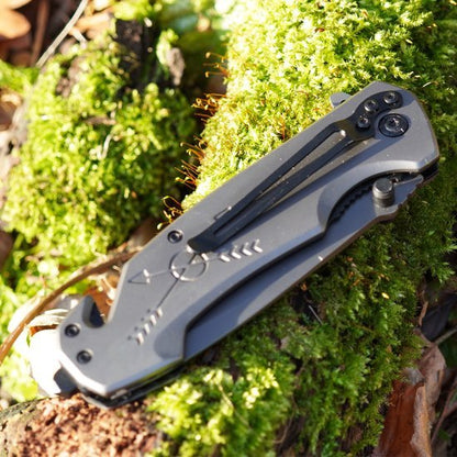 Opgevouwen scherp mes met metalen handvat liggend op groen mos in zonlicht