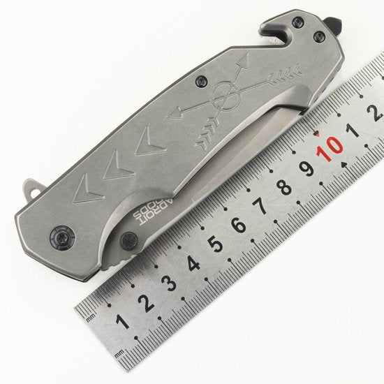 gevouwen metalen zakmes met gegraveerde pijlen naast een metalen liniaal
