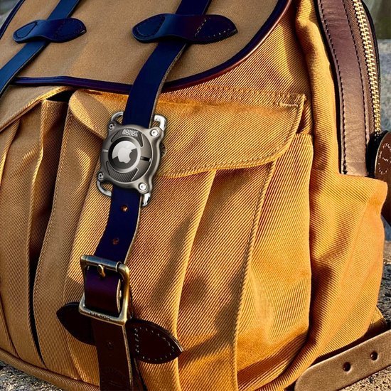 Close-up van een okergele rugzak met blauwe leren riemen en metalen gespen en sluiting