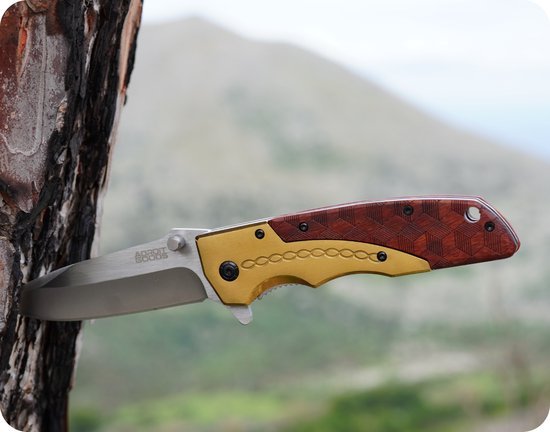 Openslaand zakmes met houten handvat en roestvrijstalen lemmet tegen een boomstam geplaatst.