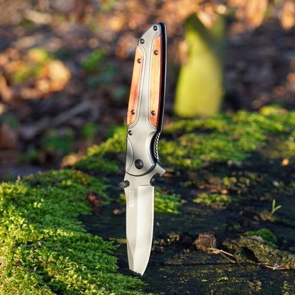 Opent mes met houten handvat en metalen lemmet geplaatst op mosgroene ondergrond in natuur.