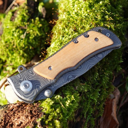 Gesloten zakmes met houten handgreep op mos bedekt hout in natuurlijk licht