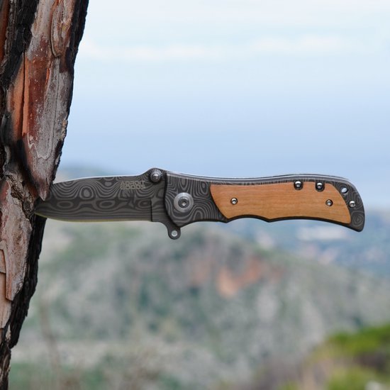 Openslaand mes met houts handvat en patroon op lemmet in boomstam geplaatst buitenlucht