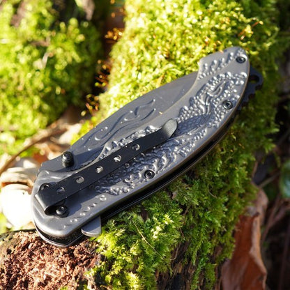 Opgevouwen zakmes met gedetailleerd handvat liggend op mosgroene bosgrond